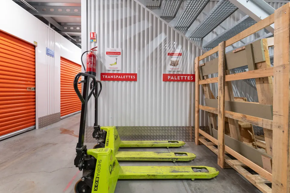 Transpalette et palettes devant les box orange