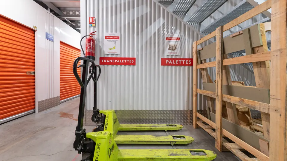 Transpalette et palettes devant les box orange